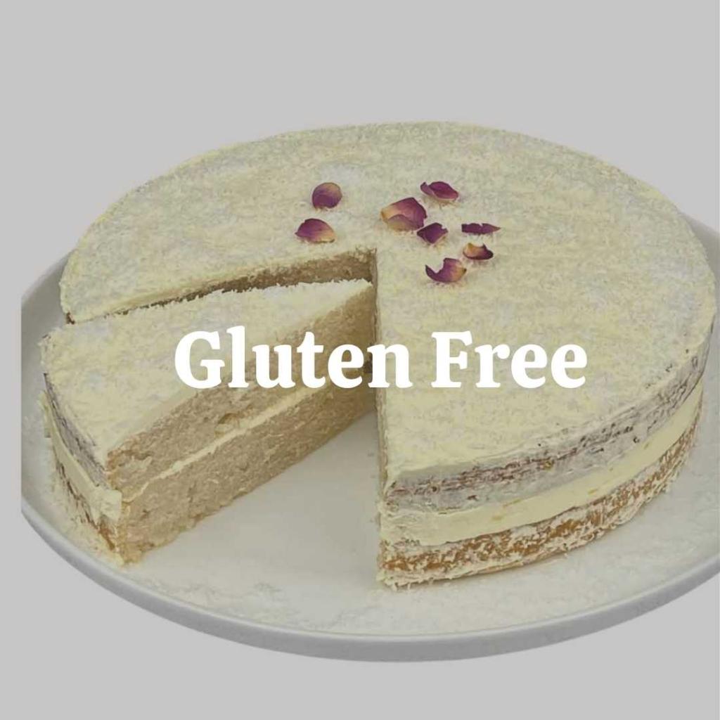 Assorted gluten-free cakes displayed on a white table. These cakes are free from gluten, making them suitable for individuals with gluten sensitivities or celiac disease